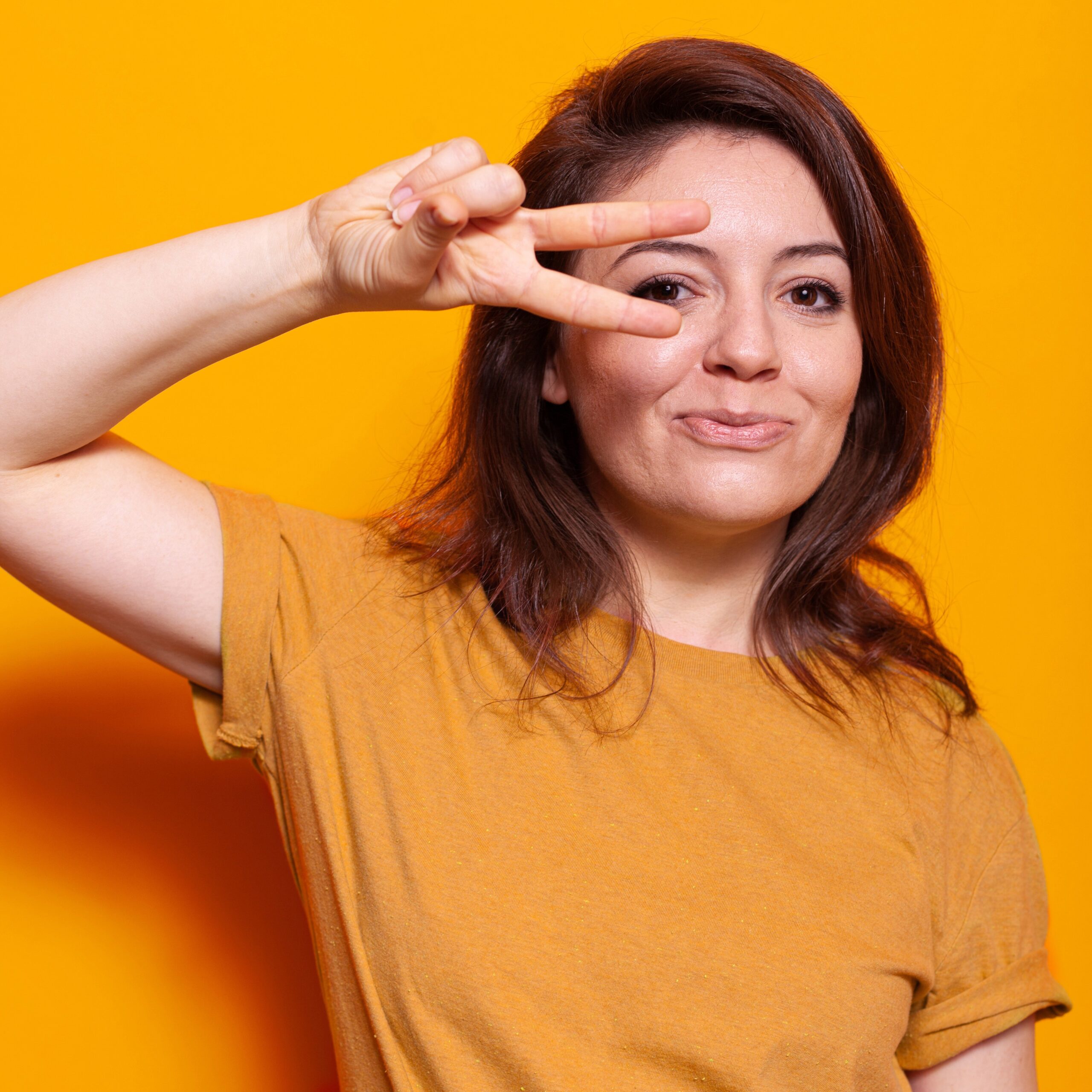 Portrait of cheerful woman making peace sign with two fingers
